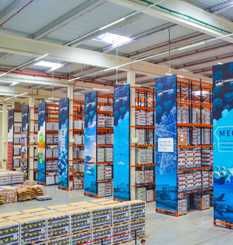 Pasillo de almacén con señalización de seguridad y estanterías de carga pesada de nuestra empresa de marketing logístico.